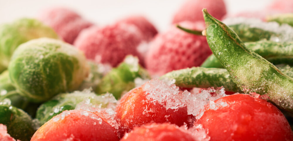 Closeup of frozen asparagus bean pods and cherry tomatoes with strawberries: frozen food concept.
